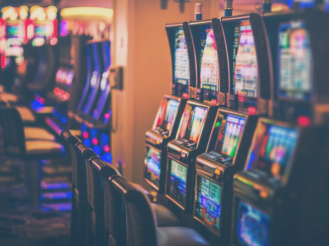 Row of slot machines in a casino, symbolizing ZeroTier's use in securing commercial gaming, POS, and high-stakes financial networks.