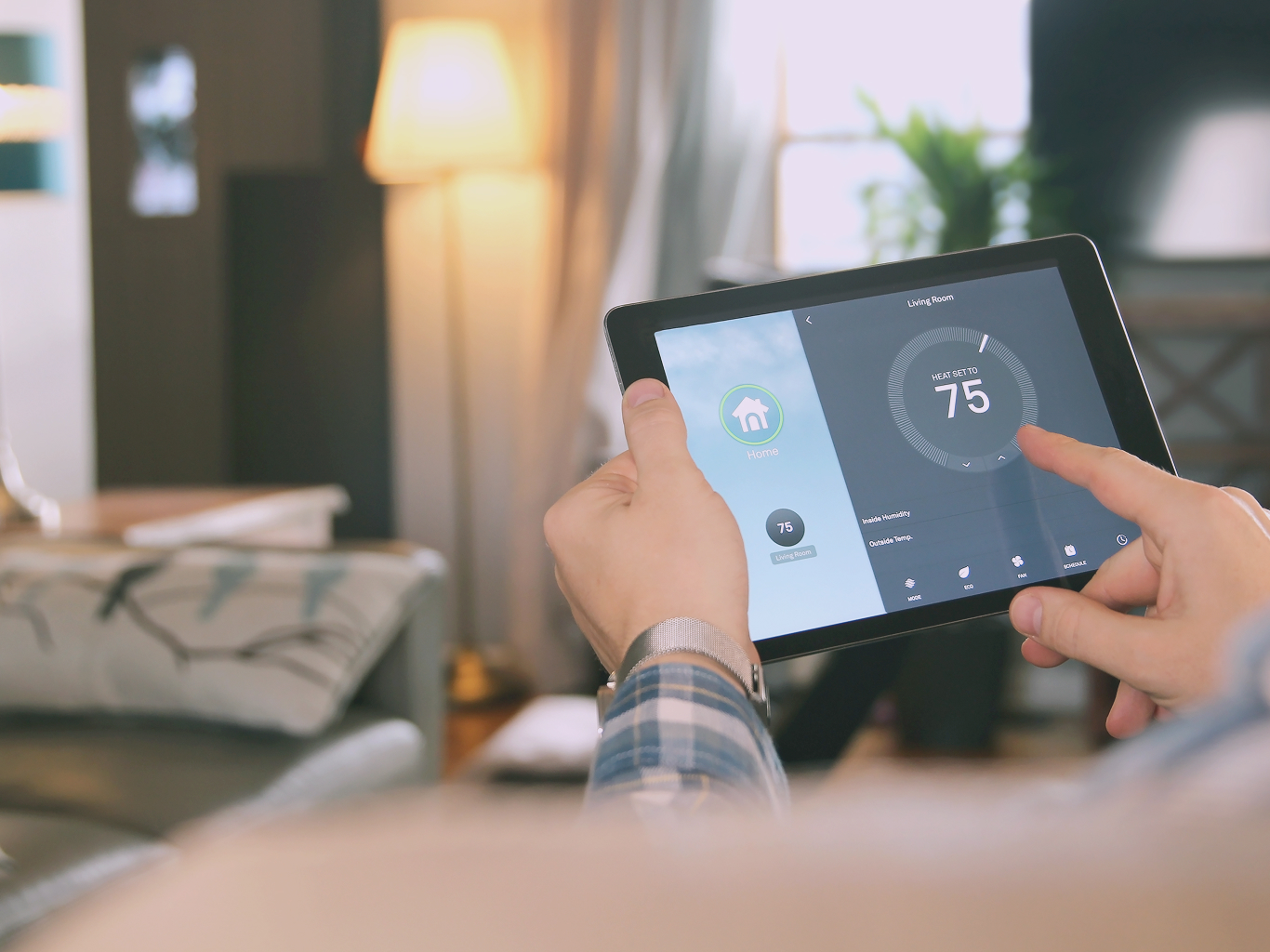 Hands holding a tablet controlling a smart thermostat, symbolizing secure remote access for home automation and residential IoT devices.